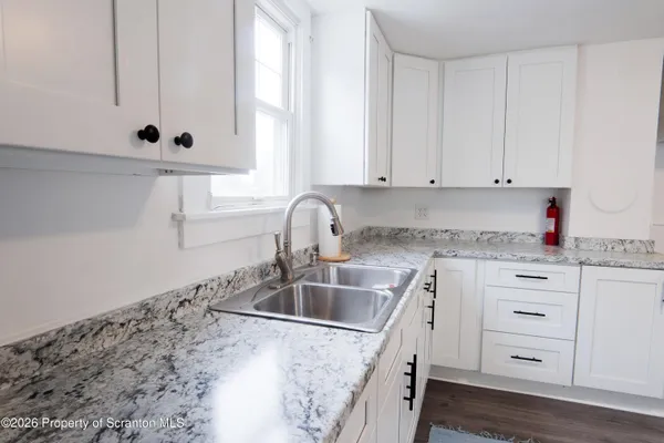 a kitchen with granite countertop white cabinets and sink