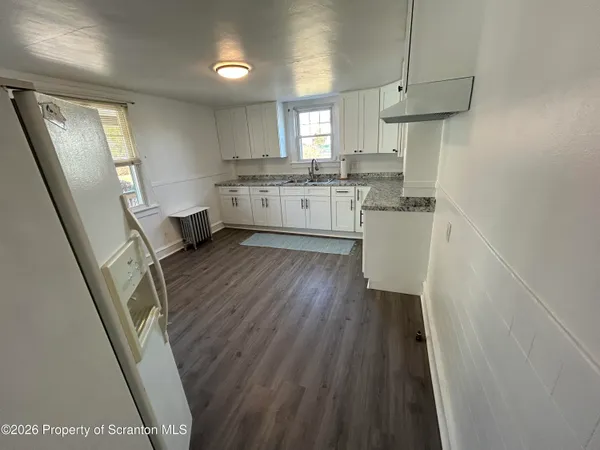 a kitchen with stainless steel appliances granite countertop refrigerator a sink dishwasher a stove and white countertops with wooden floor