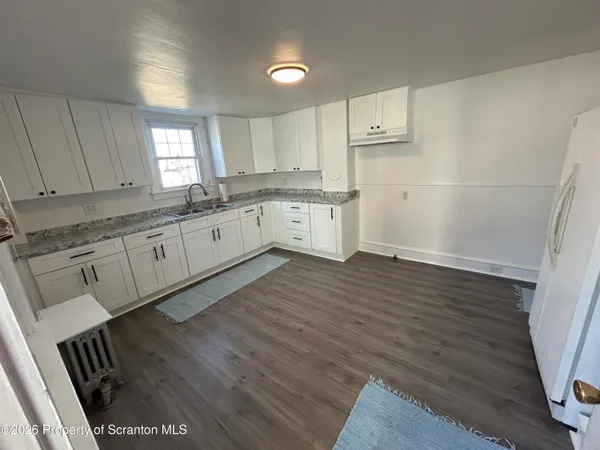 a large kitchen with granite countertop a stove a sink dishwasher and a refrigerator with wooden floor