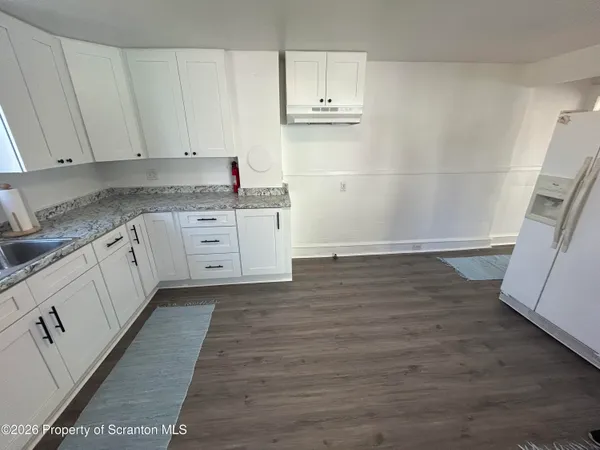 a kitchen with granite countertop white cabinets and white appliances