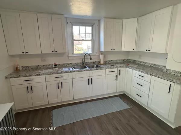 a kitchen with stainless steel appliances granite countertop a sink a stove and white cabinets