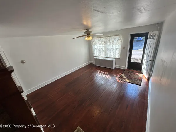an empty room with wooden floor and windows