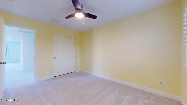 an empty room with a chandelier fan and window