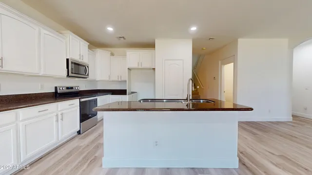 a kitchen with stainless steel appliances granite countertop a sink a stove and a refrigerator