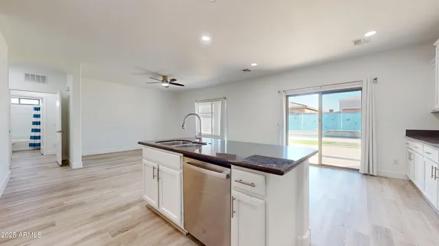 a large white kitchen with wooden floors stainless steel appliances and white cabinets