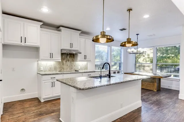 a kitchen with stainless steel appliances granite countertop a sink a stove and a wooden floor