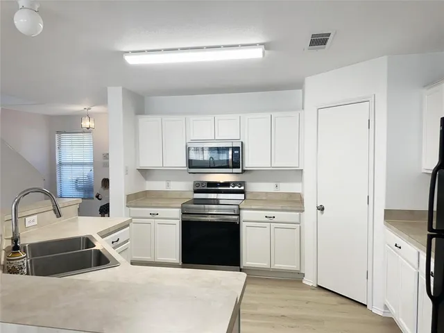 a kitchen with white cabinets and stainless steel appliances