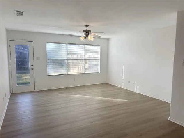 an empty room with wooden floor chandelier and windows