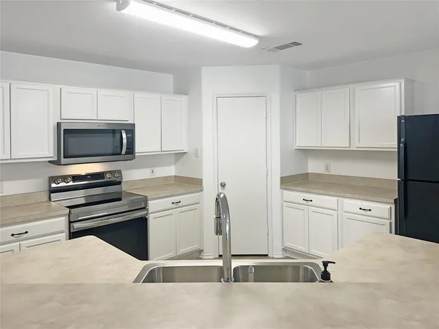 a kitchen with granite countertop a refrigerator stove and microwave