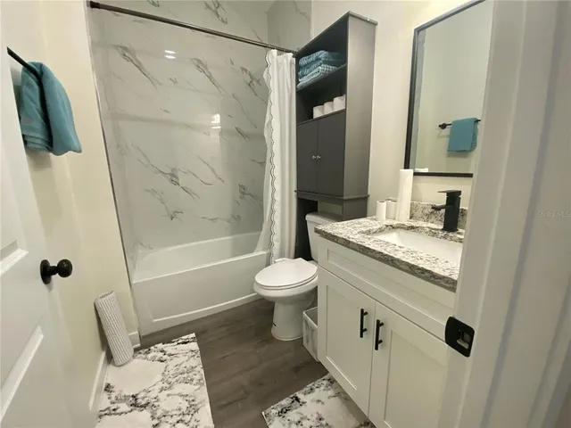 a bathroom with a granite countertop sink toilet and shower