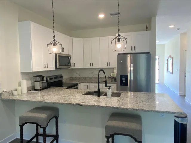 a kitchen with granite countertop a sink a center island a refrigerator wooden floor and cabinets