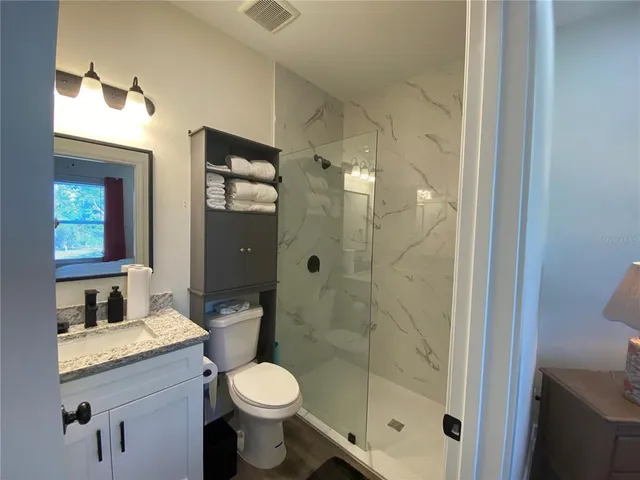 a bathroom with a granite countertop sink toilet and shower