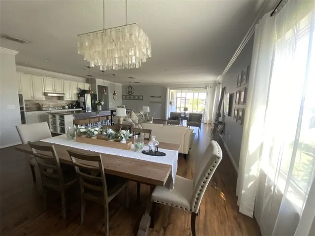 a view of a dining room with furniture a chandelier and wooden floor