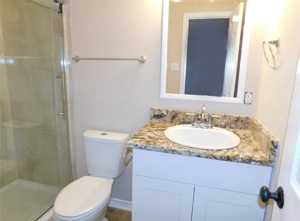 a bathroom with a granite countertop sink toilet and shower