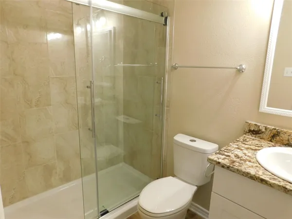 a bathroom with a granite countertop sink a mirror and shower
