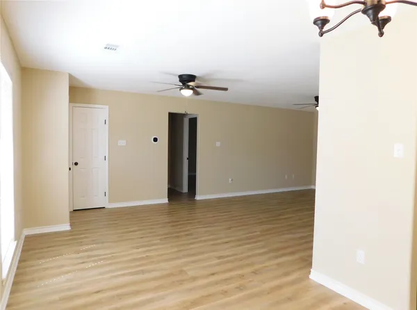 a view of a chandelier in big room with wooden floor