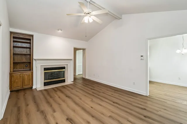 a view of a livingroom with a fireplace a ceiling fan and wooden floor