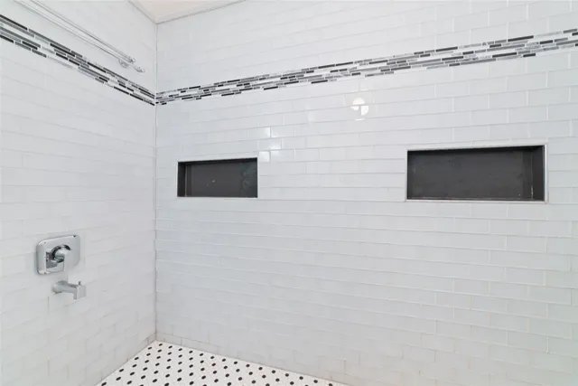 a bathroom with a shower and a tiled wall