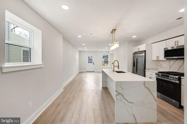 a kitchen with stainless steel appliances kitchen island granite countertop a refrigerator a sink a stove and white cabinets