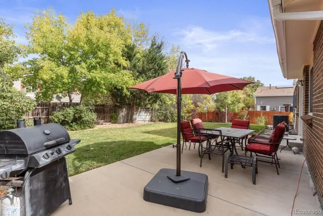 a view of a tables and chairs under an umbrella in backyard