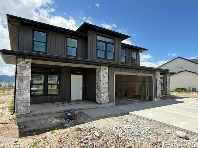 1008 West 3410 South Nibley, UT 84321 - Photo 3 of 26 Modern-style exterior featuring gray vertical siding and light-colored stone accents