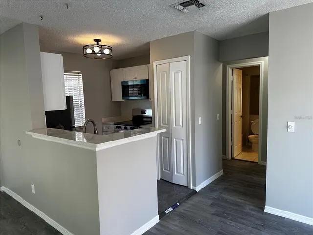 a view of kitchen with stainless steel appliances granite countertop refrigerator and a stove top oven