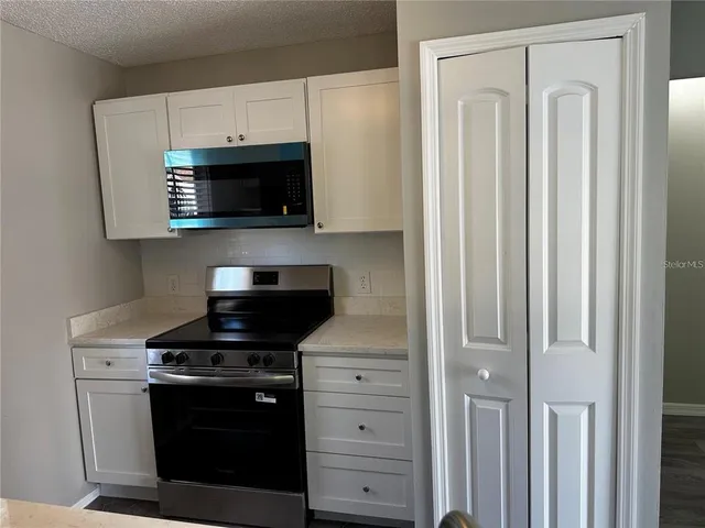 a kitchen with white cabinets and black appliances