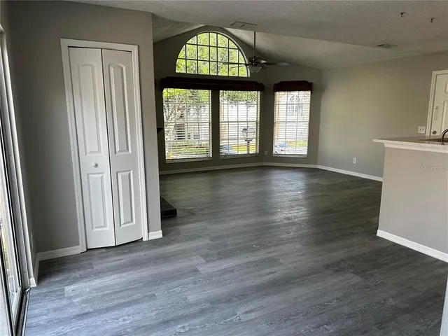 an empty room with wooden floor closet and windows