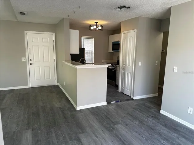 wooden floor in an empty room with kitchen and a window
