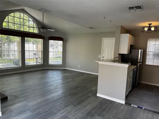 an empty room with wooden floor windows and entryway