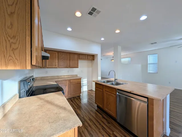 a kitchen that has a sink and a stove with wooden floor