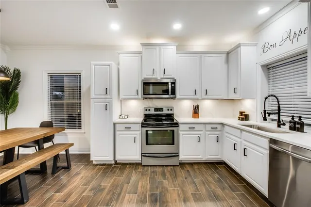 a kitchen with cabinets stainless steel appliances a sink and wooden floor