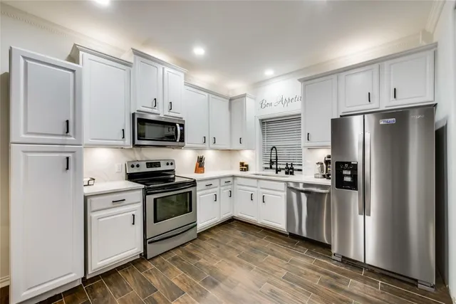 a kitchen with stainless steel appliances granite countertop a refrigerator stove a sink and white cabinets