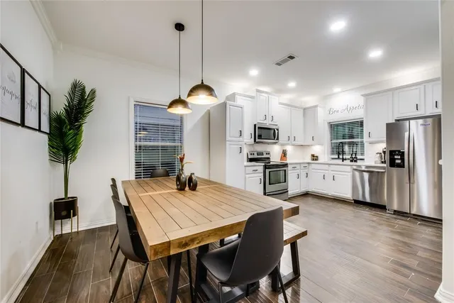 a open kitchen with stainless steel appliances granite countertop a stove refrigerator dining table and chairs