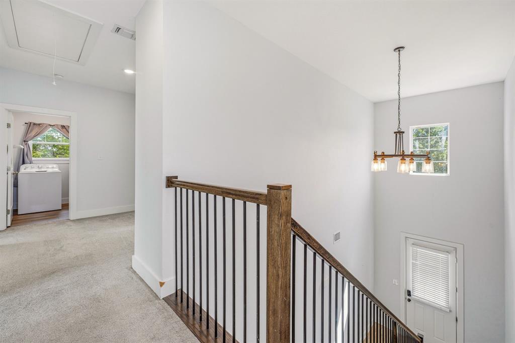 745 North Miller Avenue Stephenville, TX 76401 - Photo 14 of 31 Upper-level hallway featuring a wood-finish staircase railing with black metal spindles