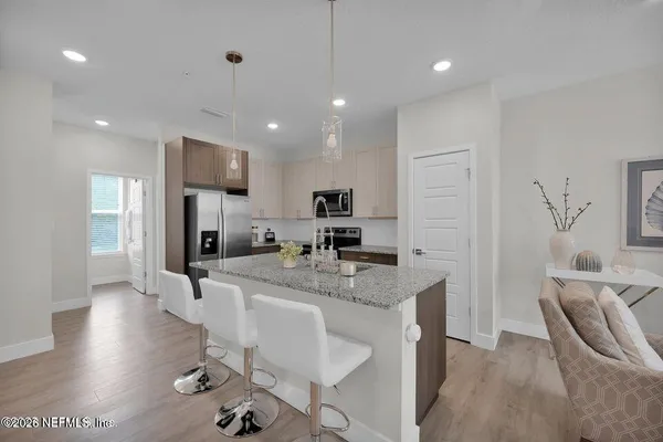 a large kitchen with sink a refrigerator and chairs