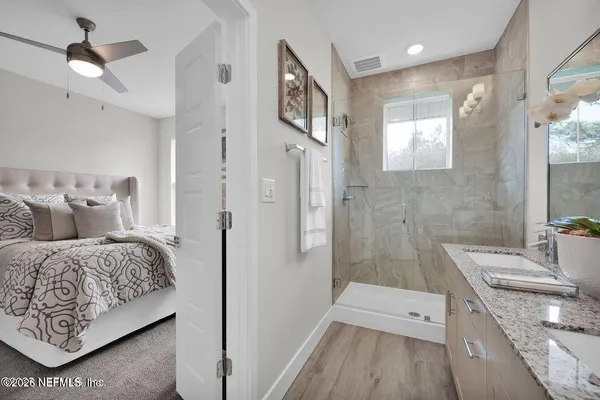 a en suite bathroom with a granite countertop double vanity sink a mirror and a shower