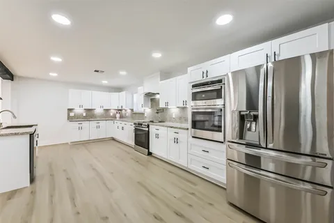 a kitchen with stainless steel appliances wooden floor sink and refrigerator
