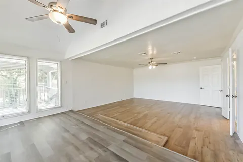 a view of an empty room with a window and a ceiling fan