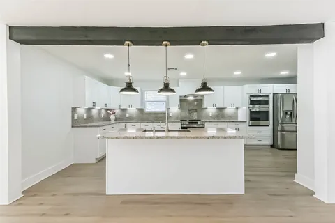 a kitchen with kitchen island granite countertop a sink cabinets and stainless steel appliances