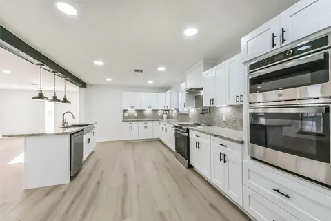a large kitchen with stainless steel appliances lots of counter top space and wooden floor