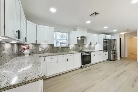 a kitchen with stainless steel appliances granite countertop a sink refrigerator and cabinets