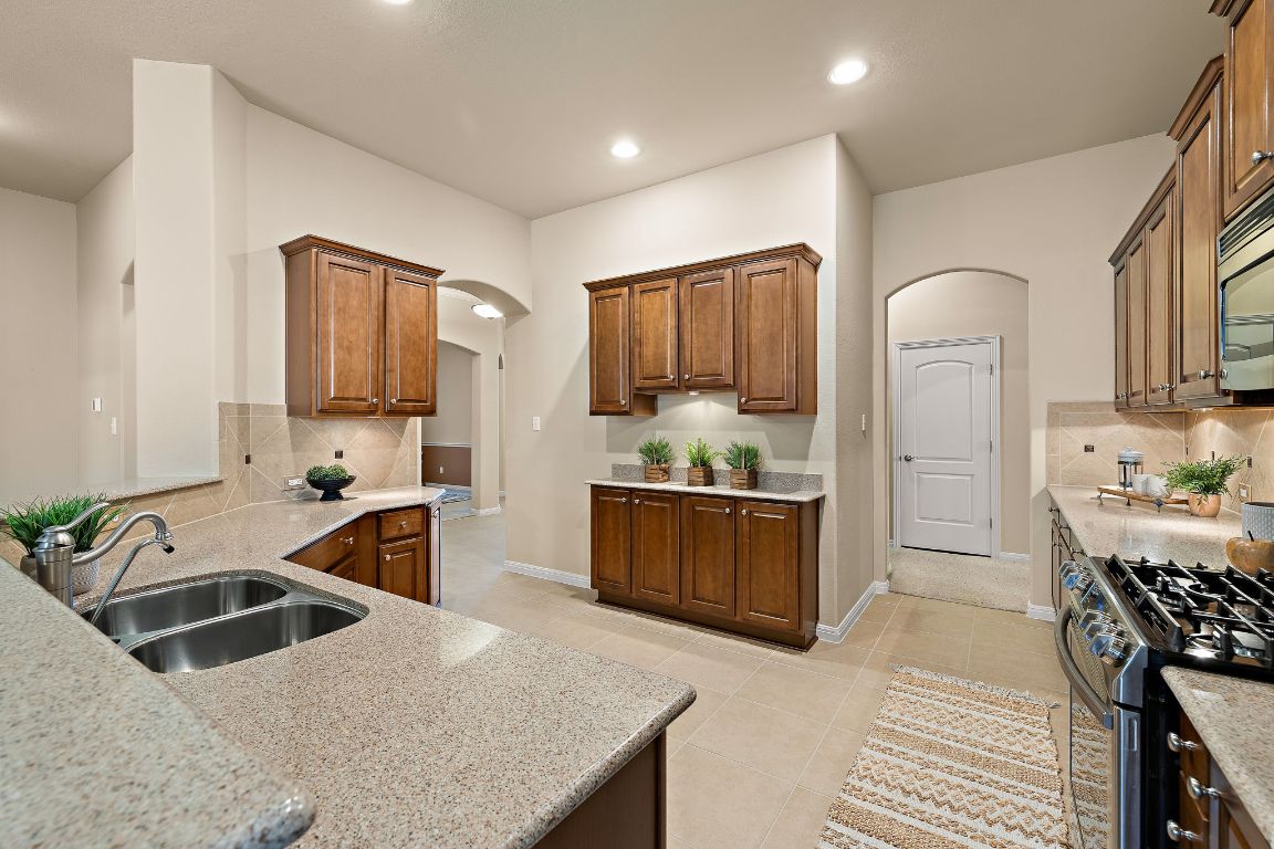3948 Sapphire Loop Round Rock, TX 78681 - Photo 18 of 40 a kitchen with granite countertop a sink stove and refrigerator