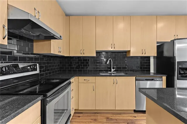 a kitchen with granite countertop a sink stove and refrigerator
