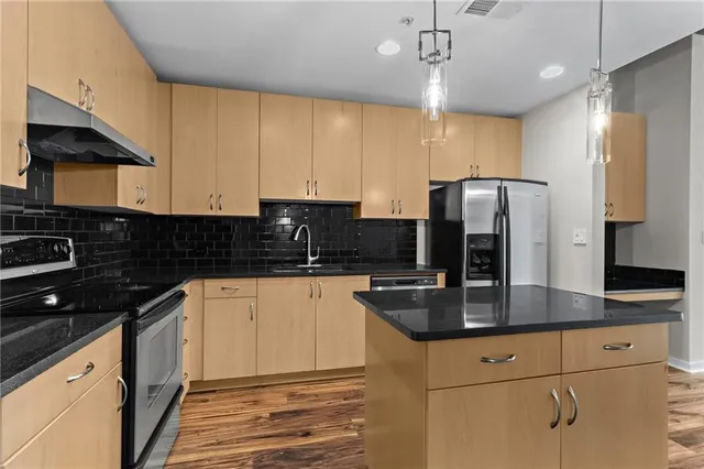 a kitchen with stainless steel appliances granite countertop a sink refrigerator and cabinets