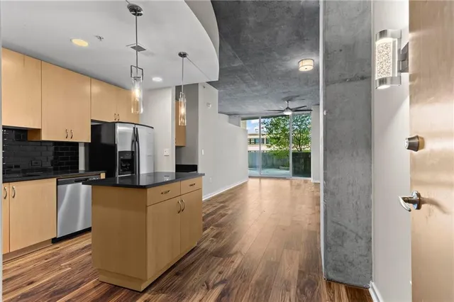 a kitchen with stainless steel appliances granite countertop a refrigerator a sink dishwasher a stove and a refrigerator with wooden floor