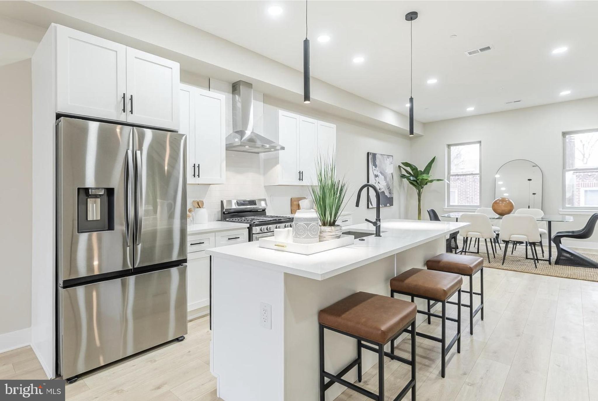 a kitchen with stainless steel appliances kitchen island a table chairs refrigerator and sink