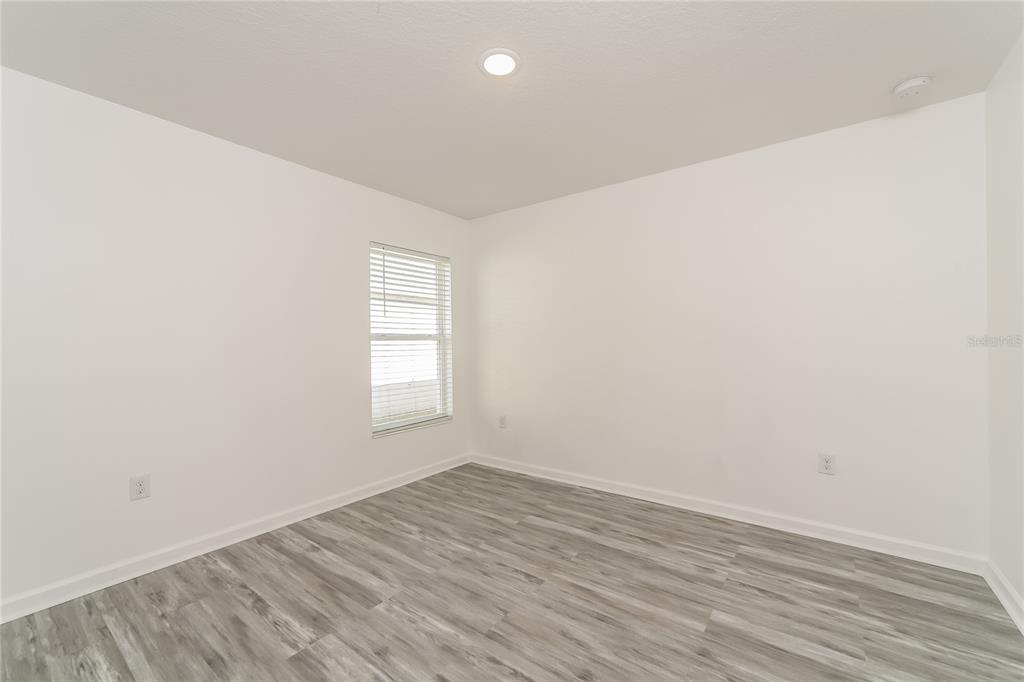 1477 Lucerne Loop Road Northeast Winter Haven, FL 33881 - Photo 12 of 15 an empty room with wooden floor and window
