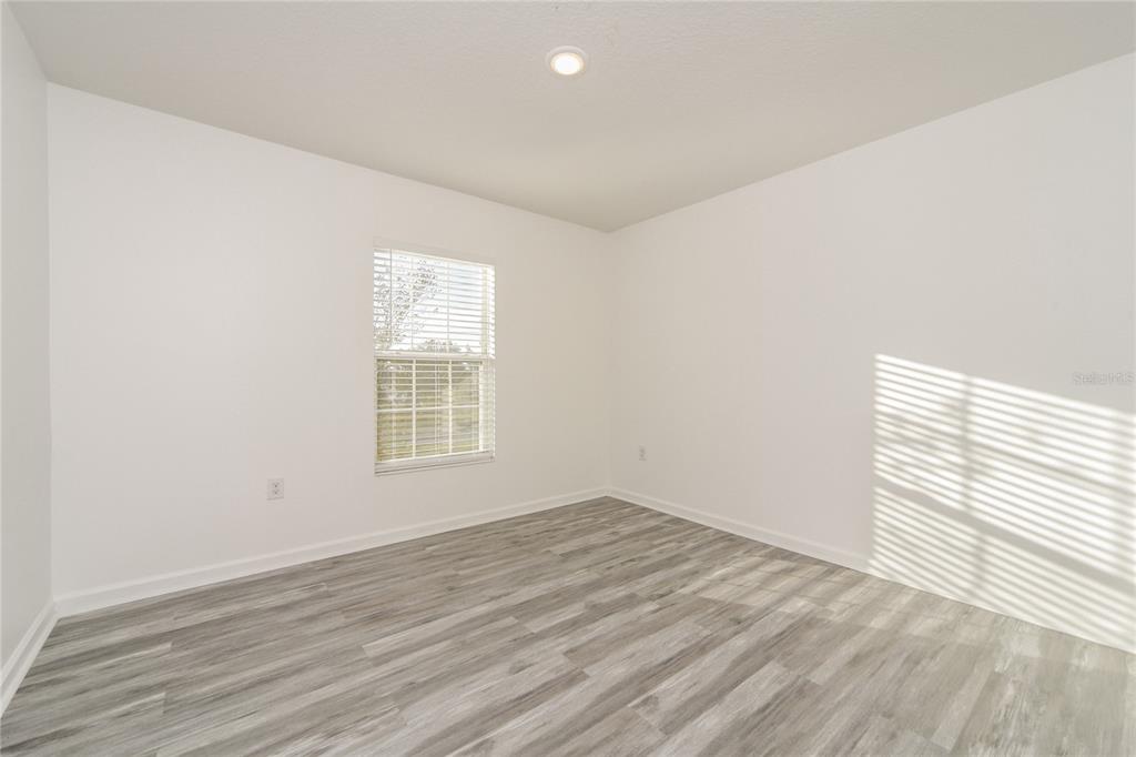 1477 Lucerne Loop Road Northeast Winter Haven, FL 33881 - Photo 13 of 15 wooden floor in an empty room with a window