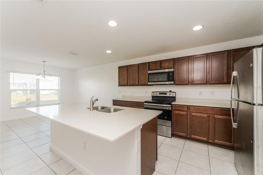 1477 Lucerne Loop Road Northeast Winter Haven, FL 33881 - Photo 5 of 15 a kitchen with stainless steel appliances a sink a stove a microwave a sink a refrigerator and cabinets